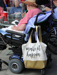 Photo with wheelchair and bag hanging with a line: "Make it happen"
