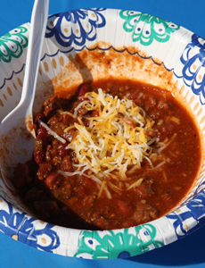 Photo of delicious chili in bowl sprinkled with cheese.
